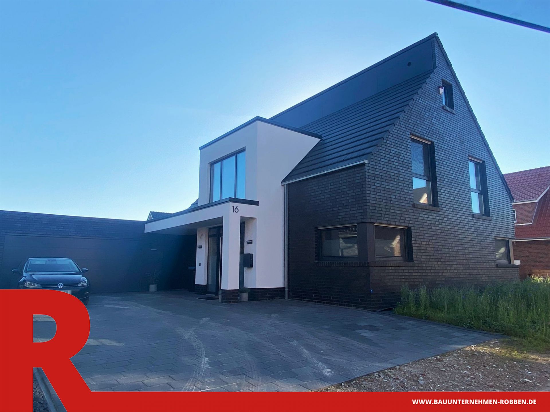 Einfamilienhaus aus dunkelroten Klinkern, mit Dachziegeln und mit einem Vorbau aus weißem Putz.