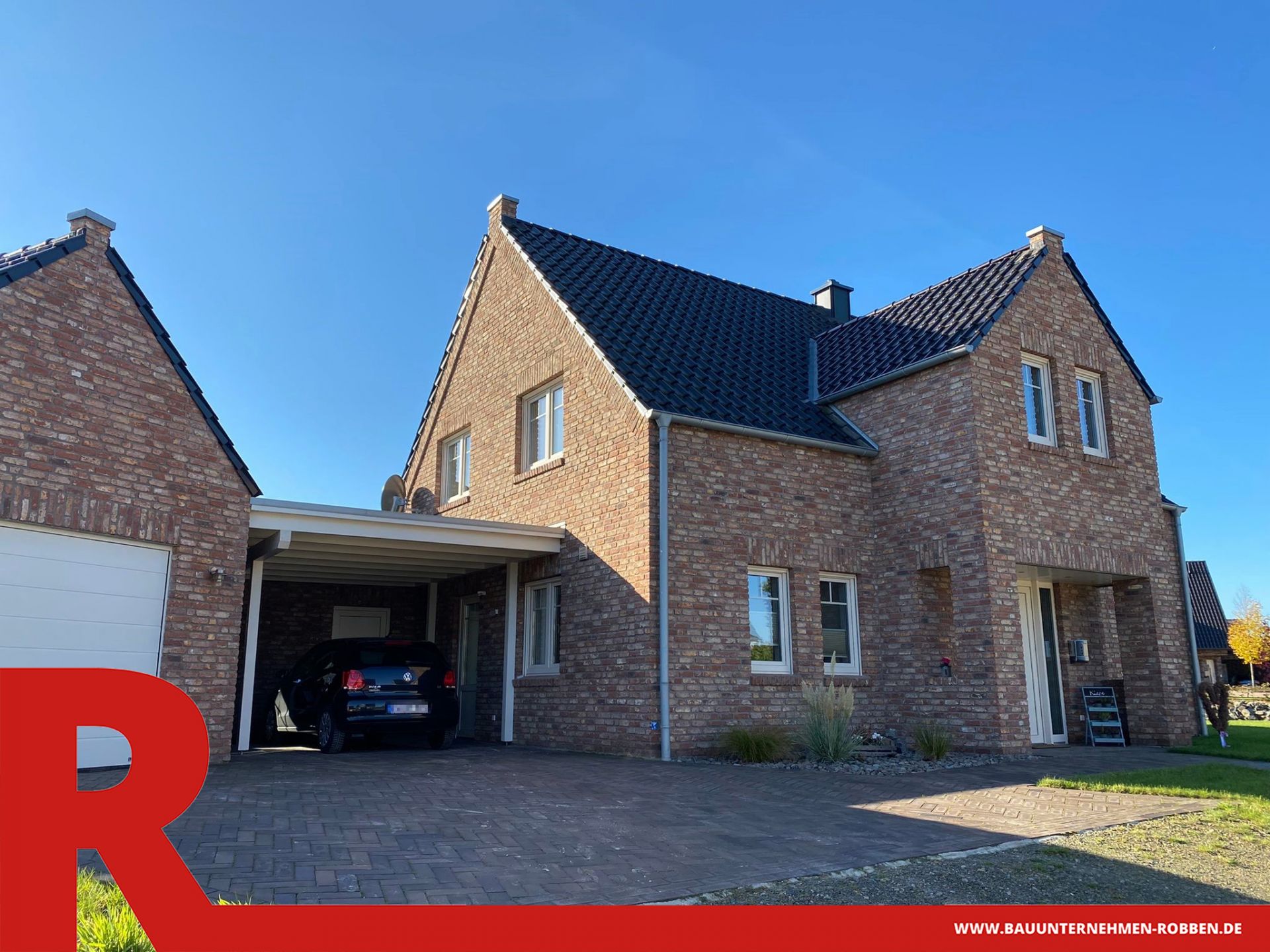 Einfamilienhaus im Landhausstil mit Ziermauerwerk, einem Carport und einer Garage.
