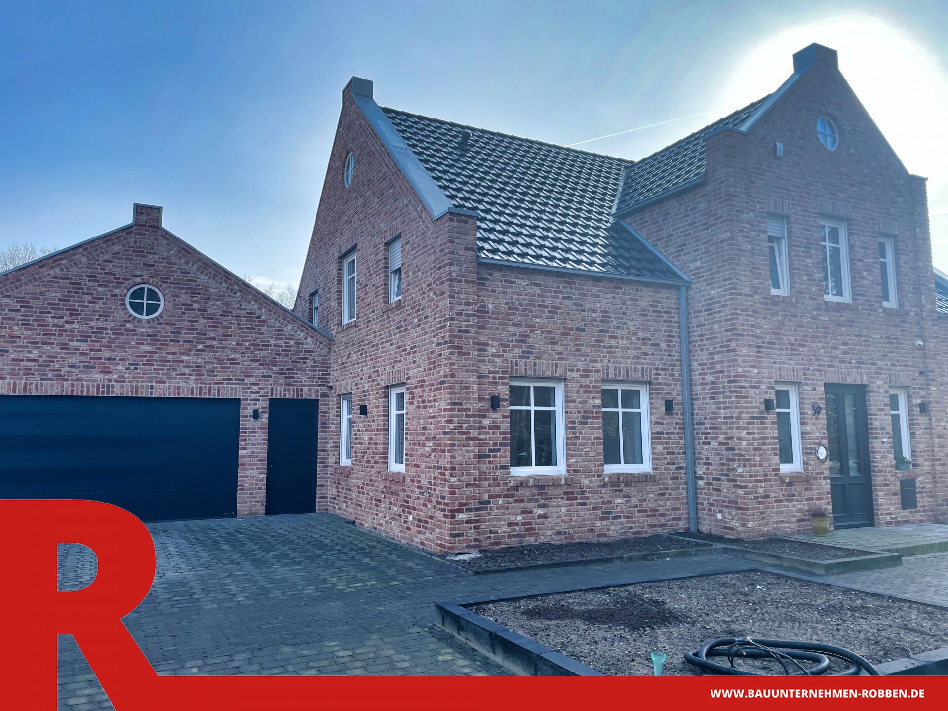 Einfamilienhaus im Landhaus-Stil mit roten Ziegeln, blauem Dach und Garage.