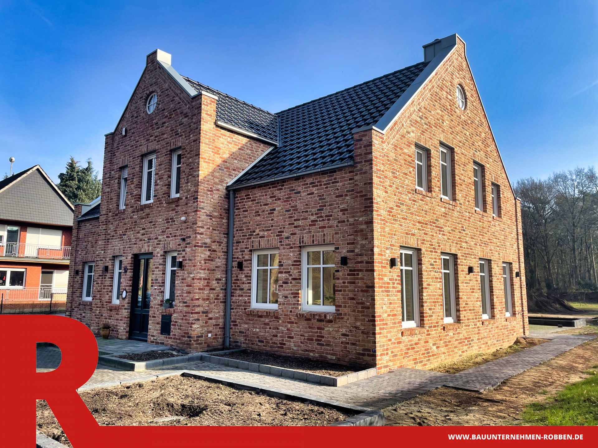 Einfamilienhaus im Landhaus-Stil mit hellroten Ziegelsteinen und blauen Dachziegeln.