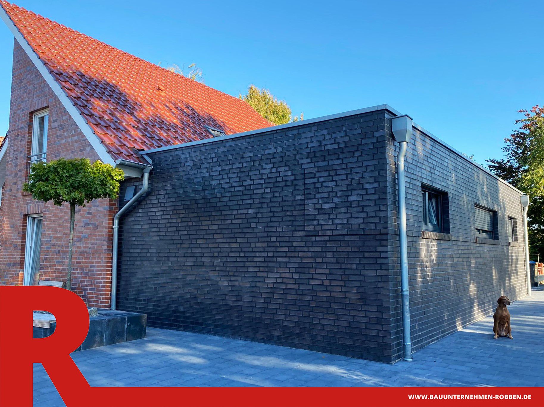 Anbau mit dunklen Ziegelsteinen in Kubus-Optik an ein Einfamilienhaus.