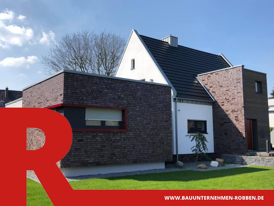 Architektenhaus mit Fassaden aus rotem Stein, braunem Holz und weißem Putz.