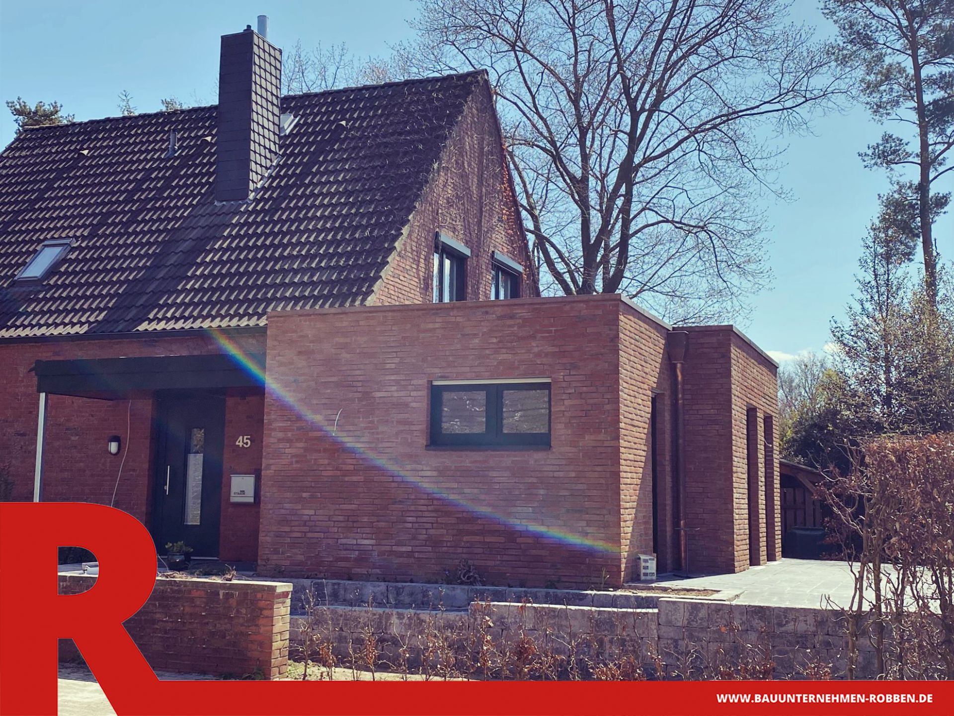 Schlüsselfertiger Anbau an ein Wohnhaus aus roten Ziegeln, der ebenerdig ist.