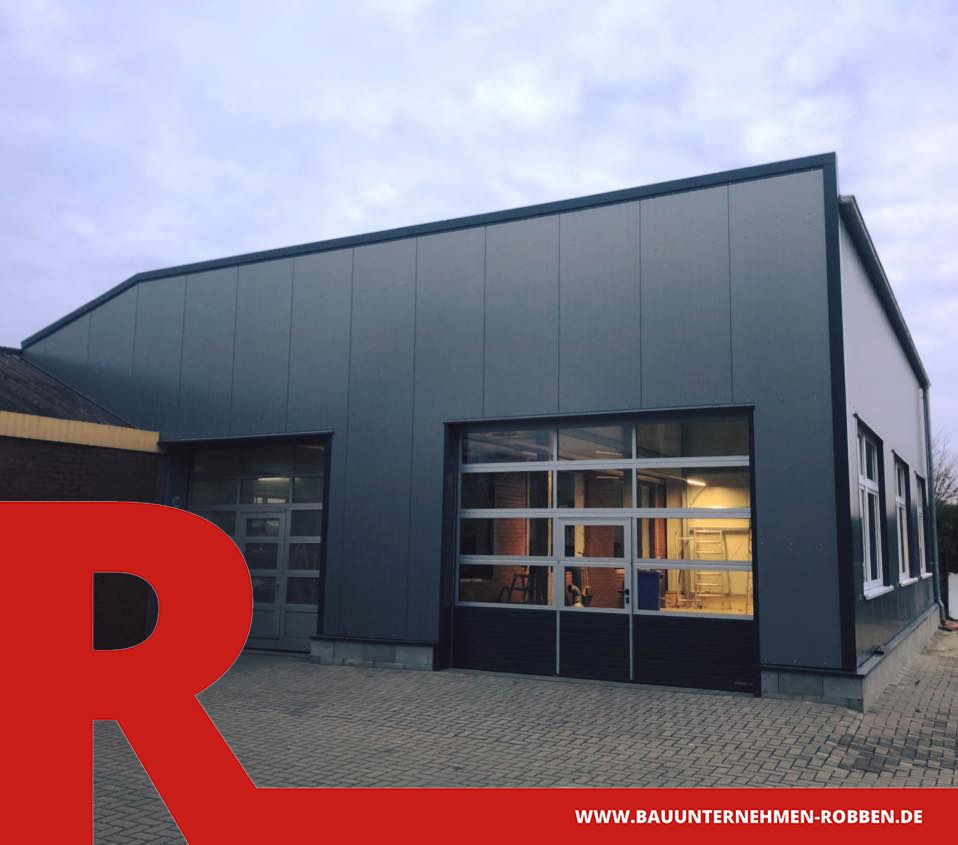 Industriehalle aus grauen Platten mit zwei großen Zugtoren als Eingang.