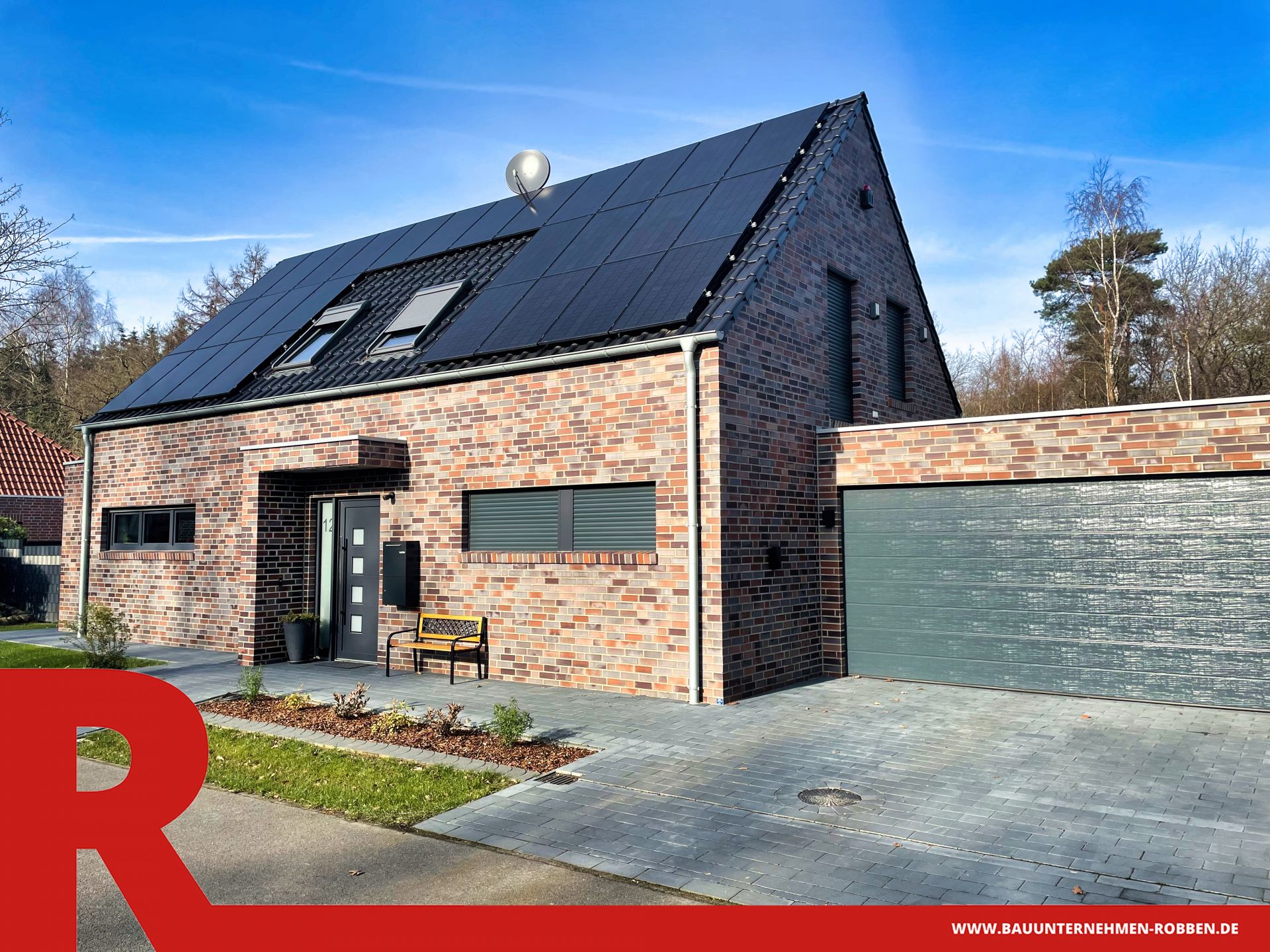 Einfamilienhaus mit hellrotem Klinker, blauen Dachziegeln, Doppelgarage und Solaranlagen.