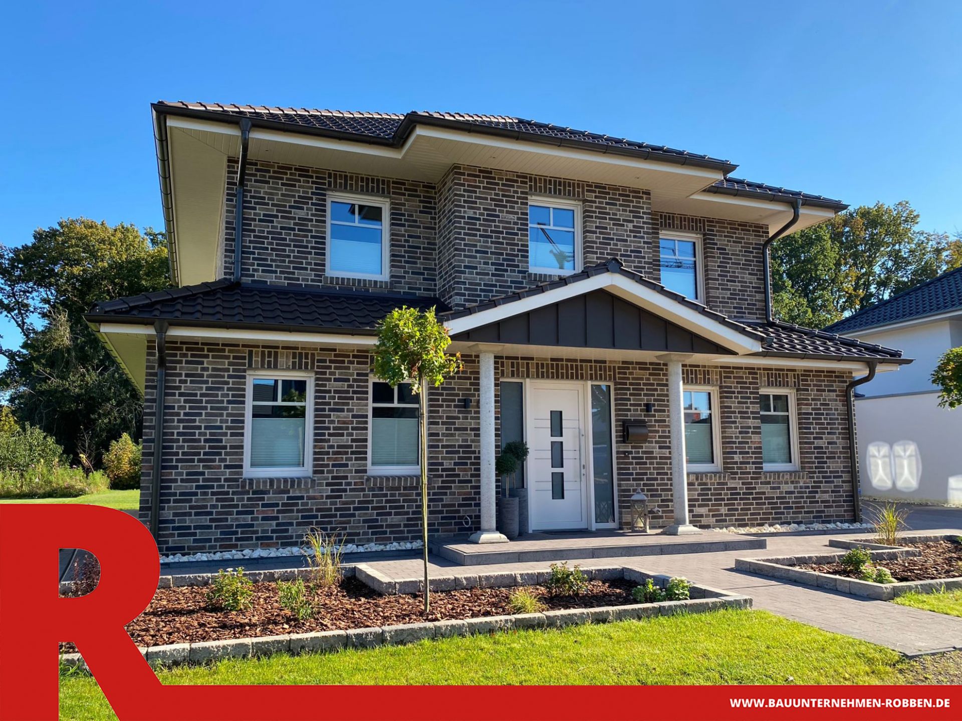 Einfamilienhaus im Stadtvilla-Stil mit schönem Garten und zwei weißen Säulen vor dem Eingang.