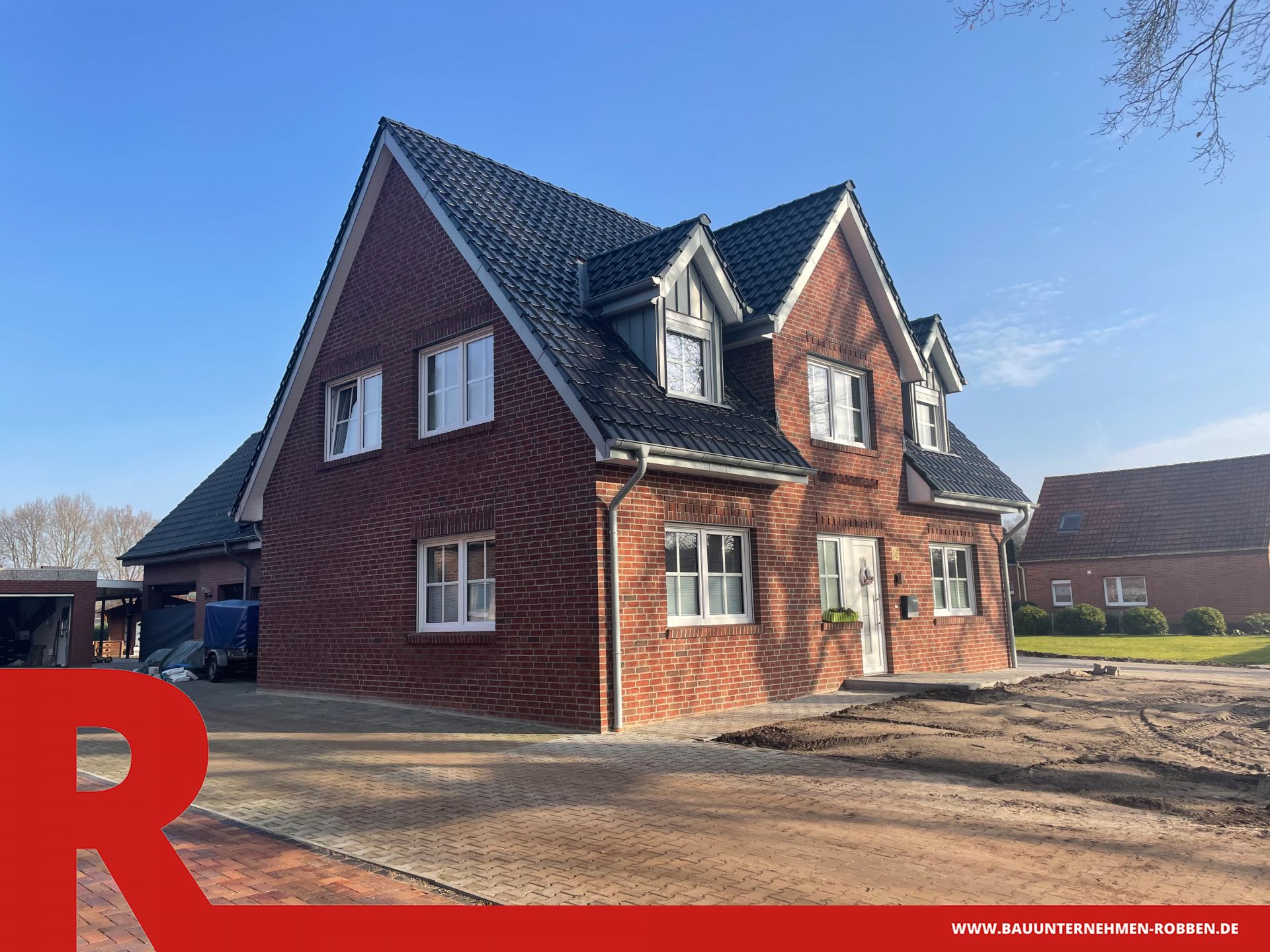 Das Bild zeigt ein Einfamilienhaus im Landhaus-Stil mit Ziermauerwerk an der Fassade.