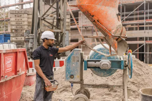 Ein Maurer richtet ein Gerät aus, um Beton zu verteilen.
