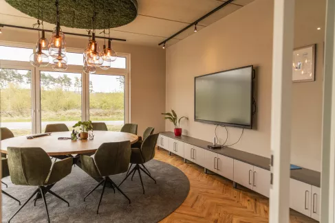 Besprechungsraum mit rundem Tisch mit 10 Stühlen und einem Smartboard.