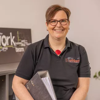Foto der Buchhalterin Anke Byl mit einem Aktenordner unter dem Arm.
