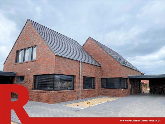 Doppelhaus Doppelhaus aus hellrotem Klinker, dunklen Dachziegeln, zwei Carports und gepflasterter Auffahrt.