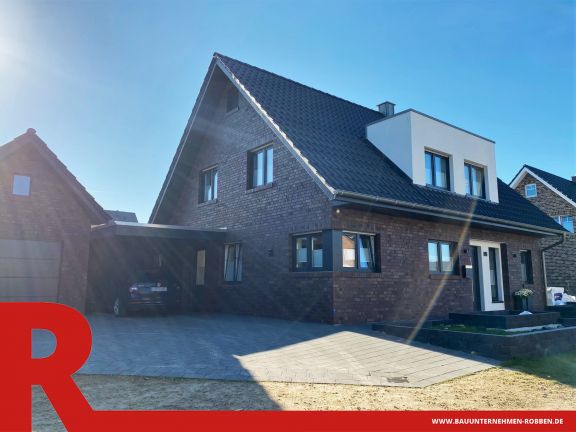 Einfamilienhaus in Haren Einfamilienhaus mit Vorbau aus weißem Putz, Carport, Garage und einer gepflasterten Auffahrt.