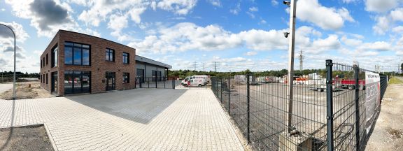 Panoramabild des Firmengel&auml;ndes mit B&uuml;rogeb&auml;ude, Lagerhallen, Parkpl&auml;tzen und Lagerplatz