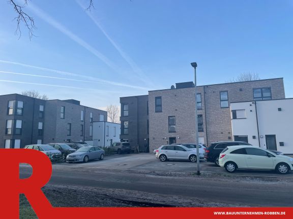 2 Mehrfamilienhäuser in Haselünne Zwei Mehrfamilienhäuser mit verschiedenfarbigen Außenfassaden und Parkplätzen davor.