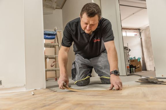 Innenausbau Ein Mitarbeiter verlegt Laminat in einem Innenausbau.