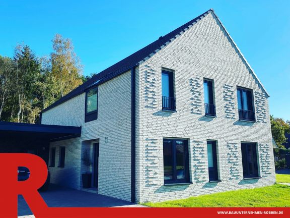 Einfamilienhaus in Haselünne Architektenhaus mit weißen Ziegelsteinen mit eingebautem Ziermauerwerk und dunklen Dachziegeln.