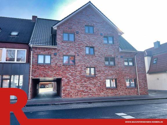 Mehrfamilienhaus in Meppen 1 Ein Mehrfamilienhaus mit roten Klinkern, blauen Dachziegeln und vielen Fenstern.