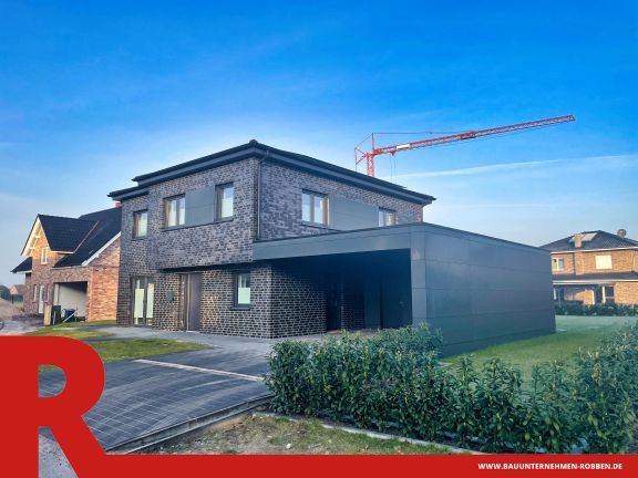 Modernes Doppelstockhaus mit dunklen Ziegelsteinen, gro&szlig;en Fenstern und einem Carport.